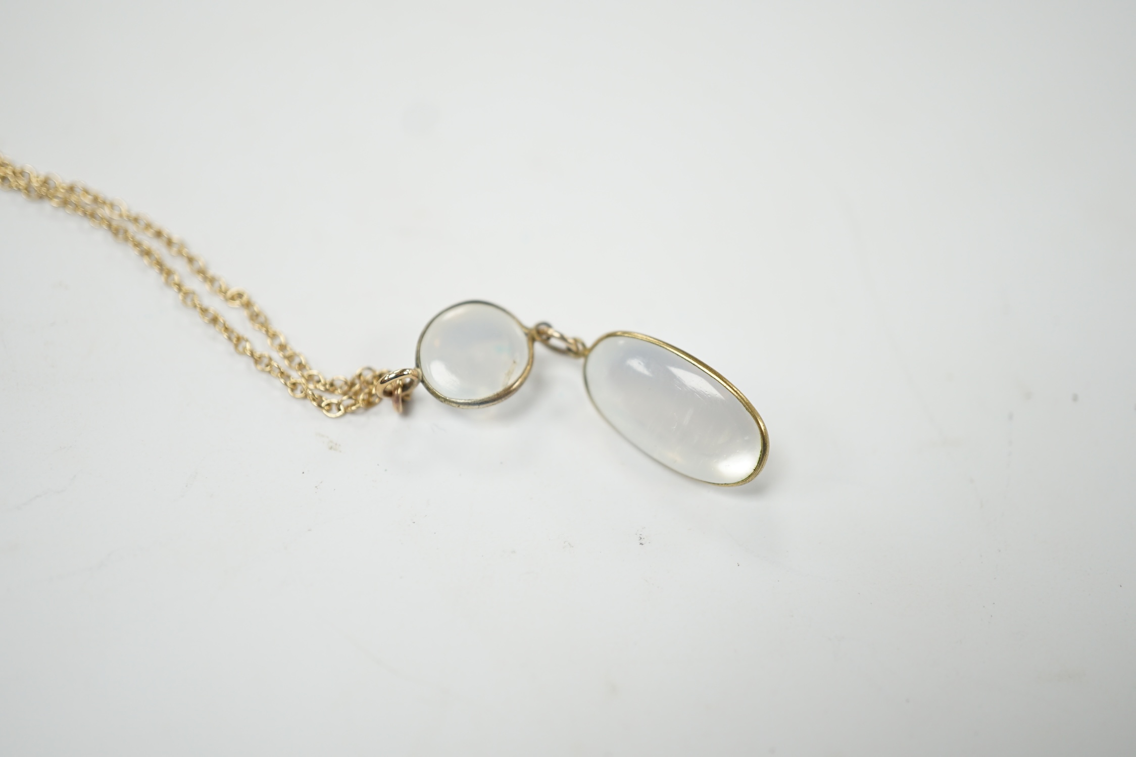 A modern 9ct gold and two stone cabochon moonstone set drop pendant necklace, overall, 47cm, gross weight 3.8 grams. Good condition.
